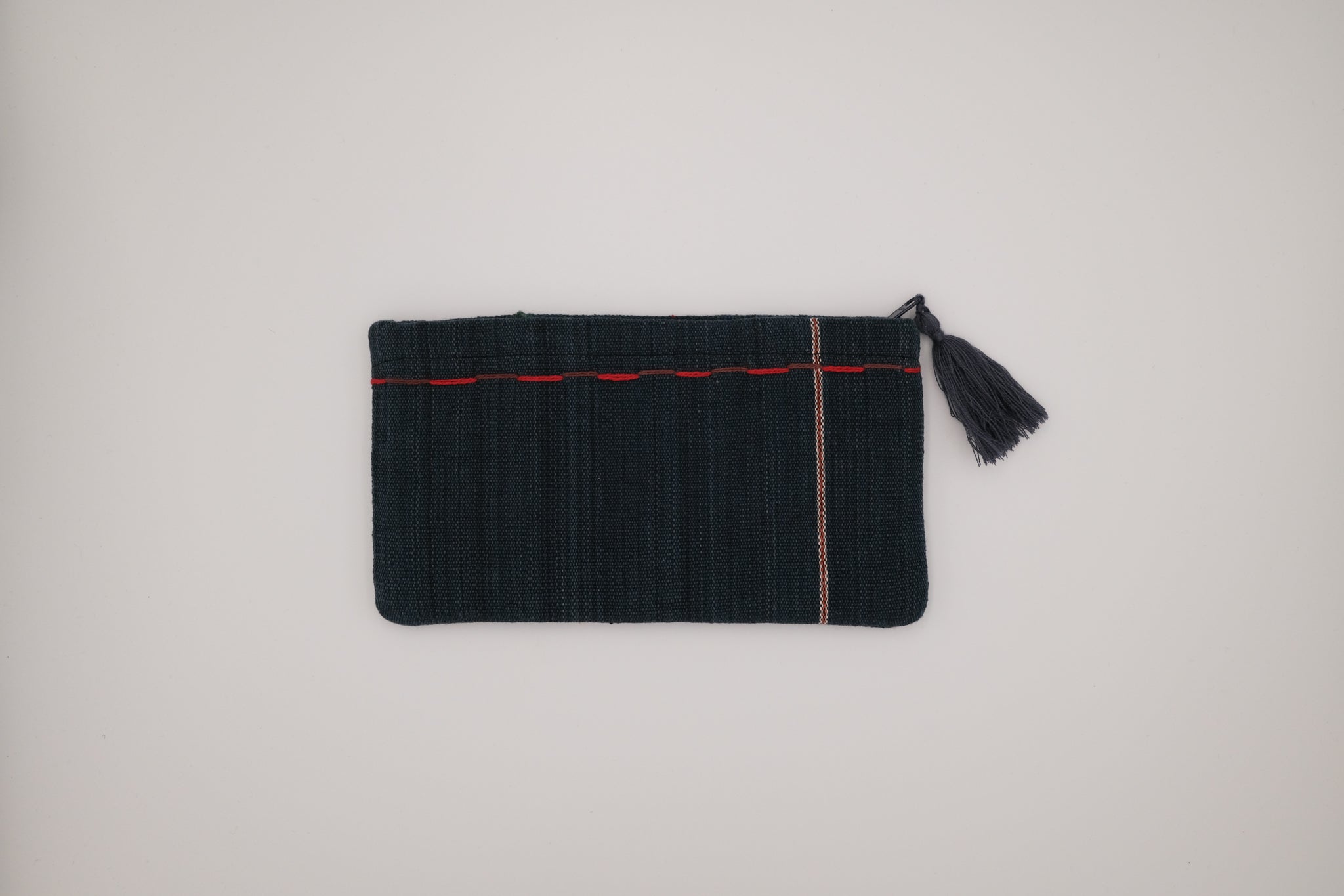 Black clutch bag with red trim and tassel on a light gray background