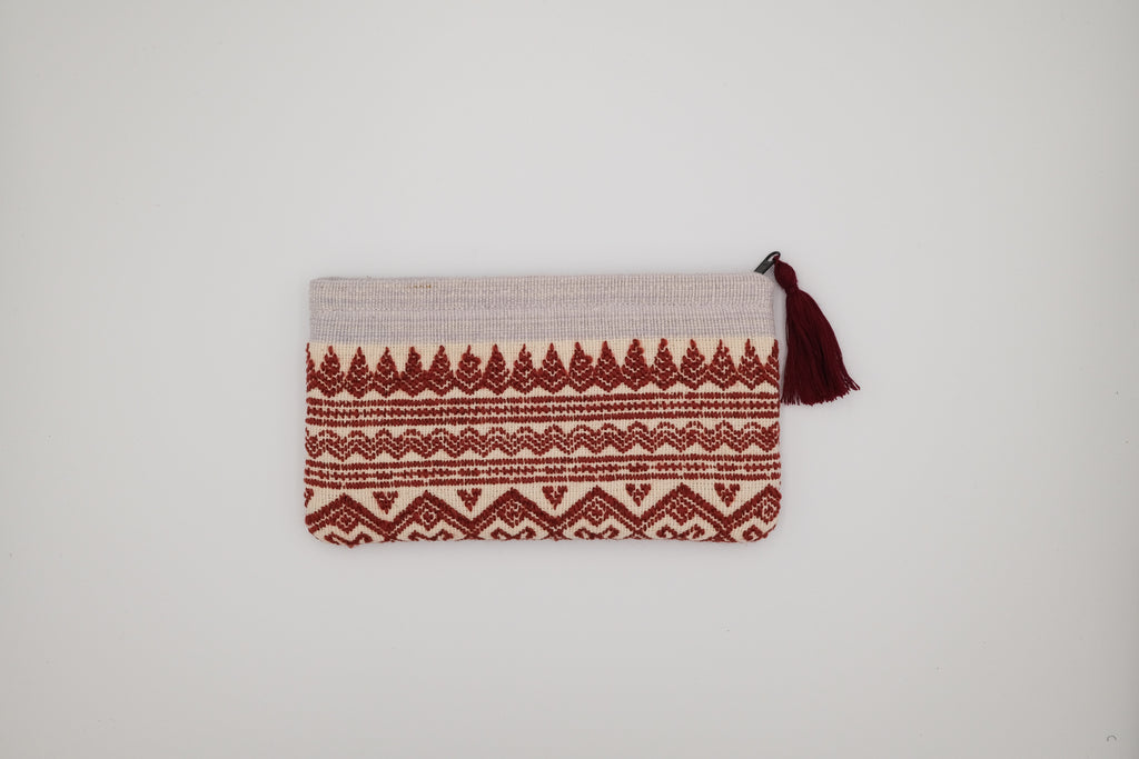 Pouch with red pattern and tassel on a light gray background
