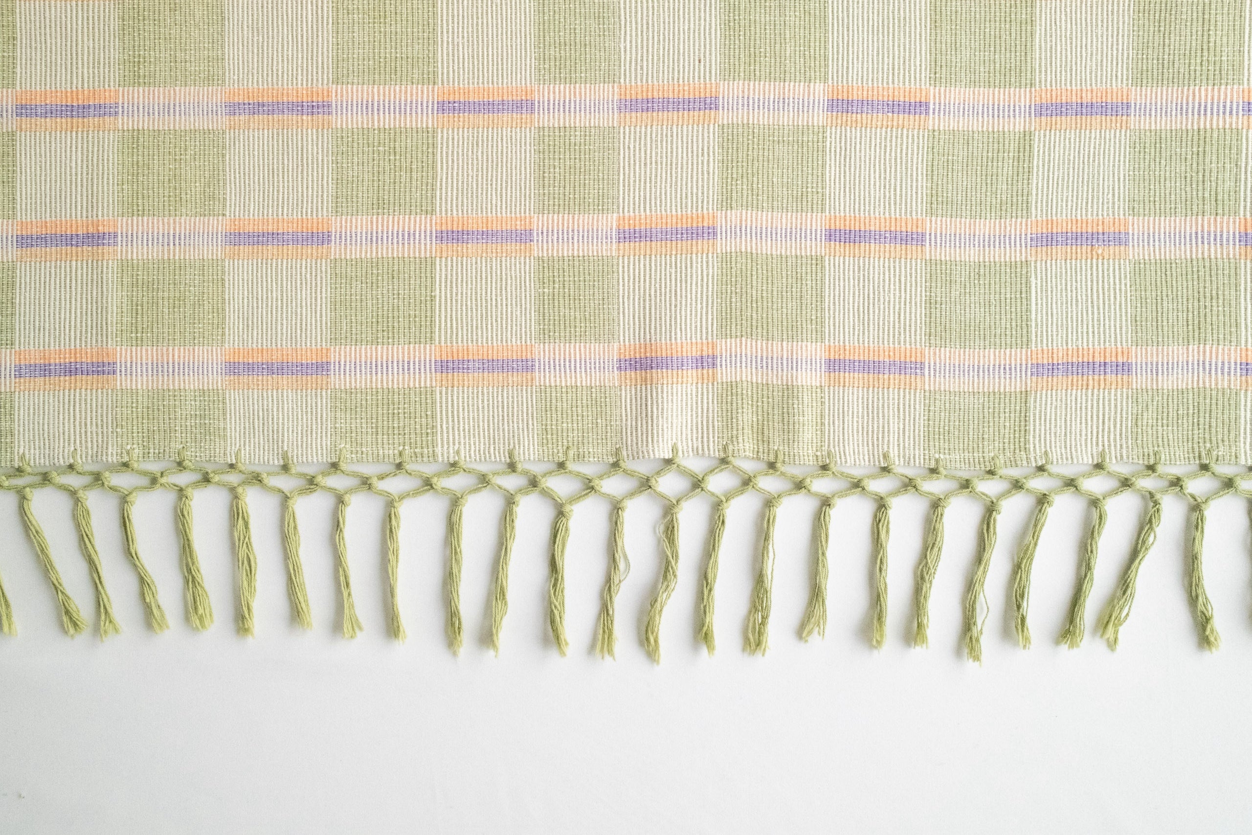 Woven laid fabric with fringe on a white background